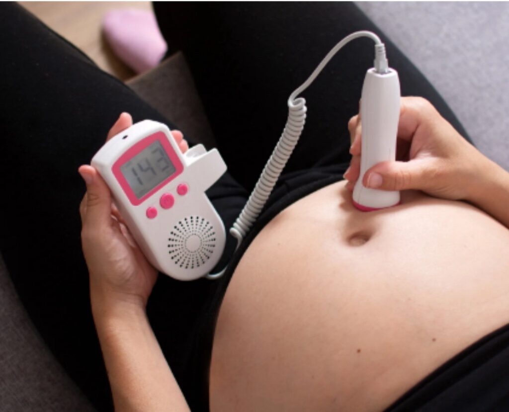 A mom listening to her baby’s heartbeat using a home doppler.